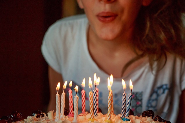 Mladá dívka sfoukává svíčky na dortu.